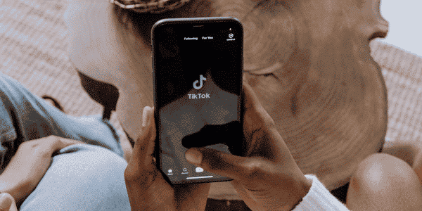 A smart phone in a person's hands with a TikTok home screen open.