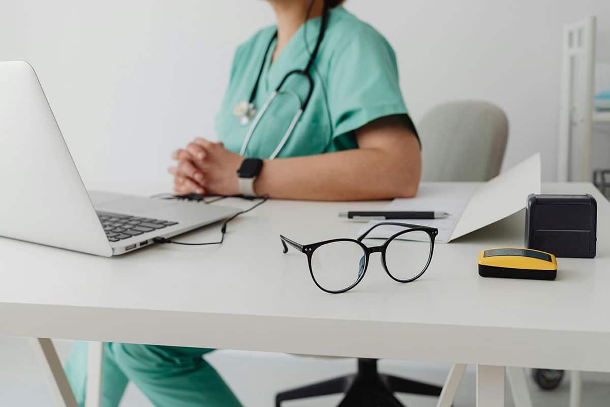 Woman in blue scrub suit using macbook-pro