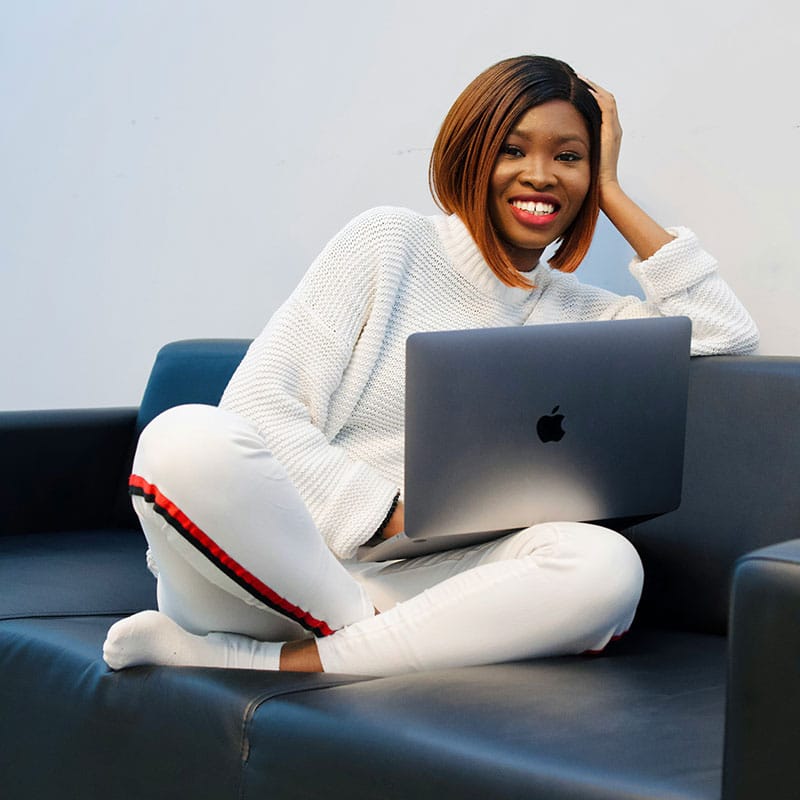 Woman in white sweater and white pants sitting on blue couch