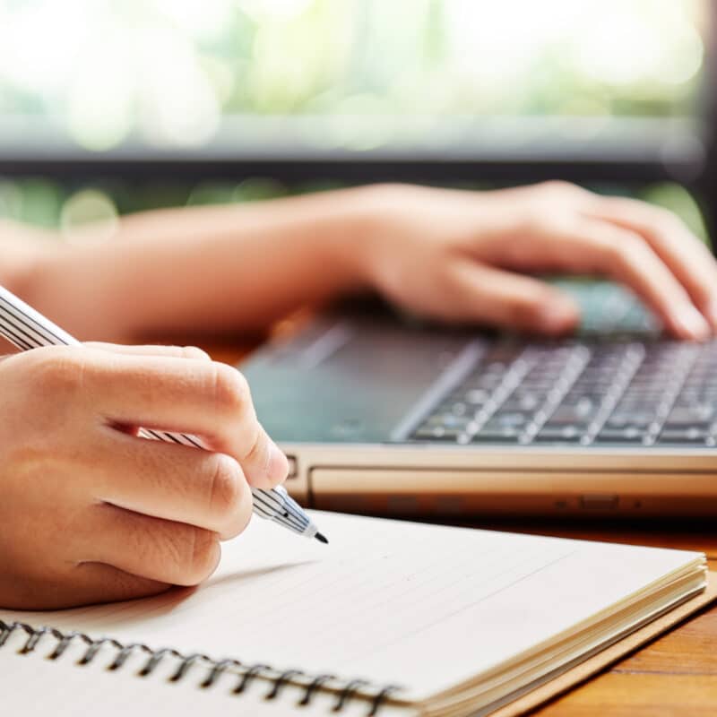 Close up hand of girl writing some data in notebook