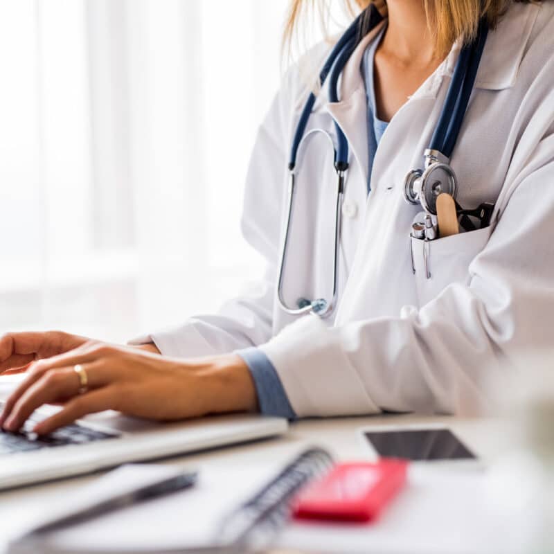 doctor typing notes on laptop