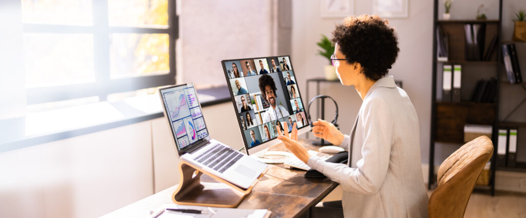 woman sitting at desk with laptop and external monitor