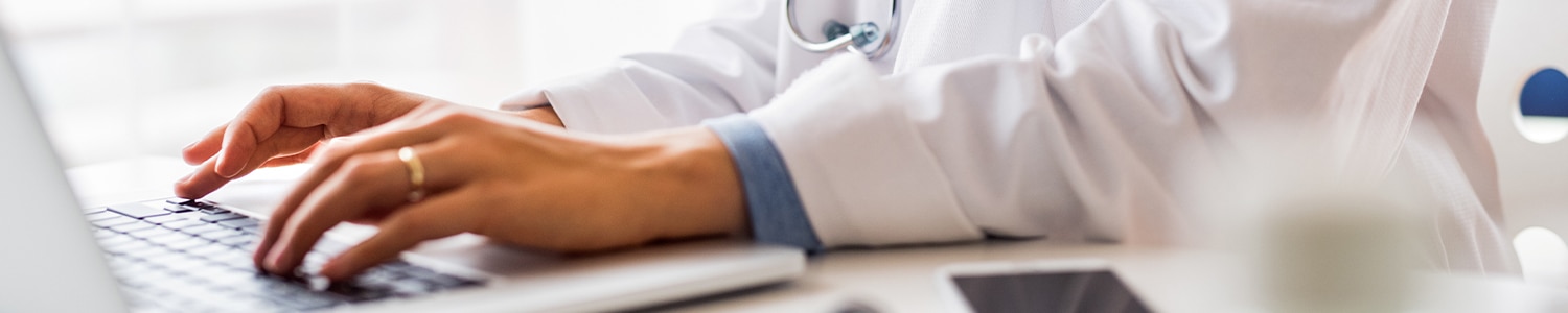 doctor sitting at laptop with hands on keyboard