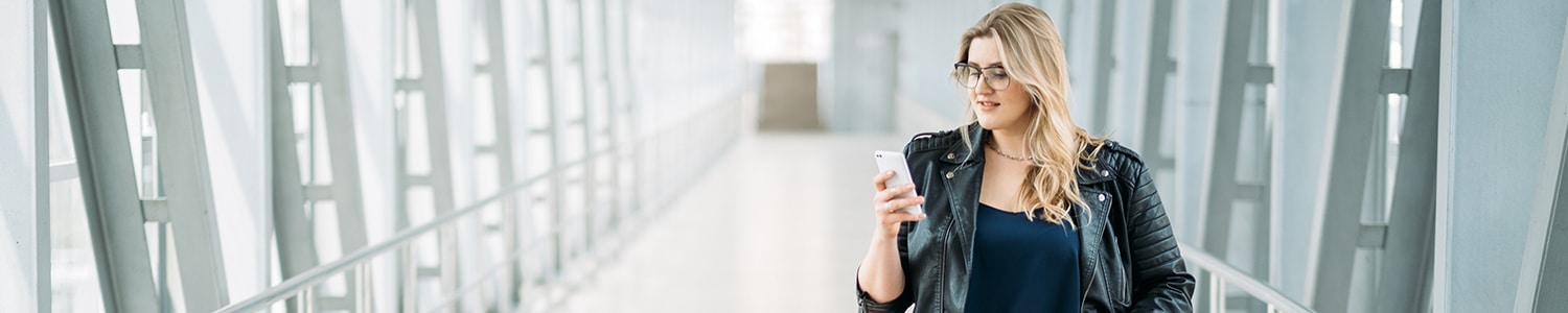 woman looking at phone while walking down hallway